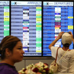 A person takes a photo of the departures board outside the international terminal at Los Angeles International Airport (LAX) August 30, 2024. The World Travel & Tourism Council reported in May 2025 findings from an economic research study that projects the U.S. is on track to lose $12.5 billion this year as international visitation declines. (Photo by Mario Tama/Getty Images)