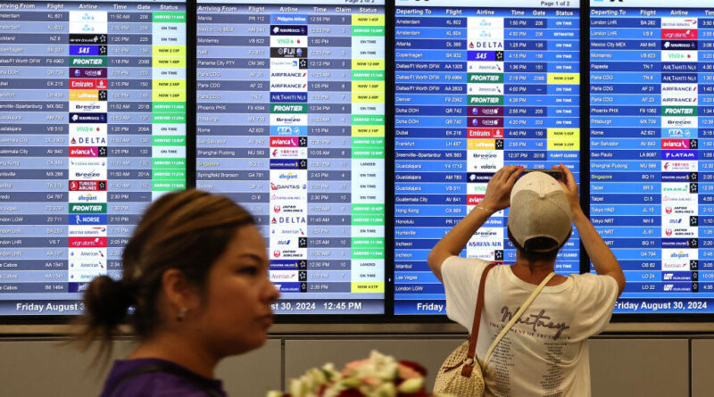 A person takes a photo of the departures board outside the international terminal at Los Angeles International Airport (LAX) August 30, 2024. The World Travel & Tourism Council reported in May 2025 findings from an economic research study that projects the U.S. is on track to lose $12.5 billion this year as international visitation declines. (Photo by Mario Tama/Getty Images)